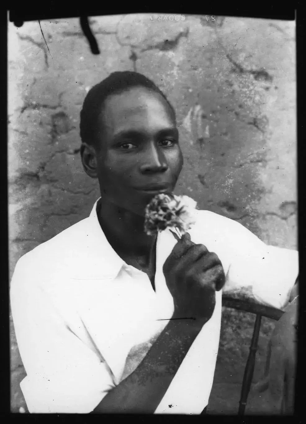 Black-and-white portrait of Seydou Keïta holding a flower, capturing the Malian photographer known as a pioneer of African portrait photography