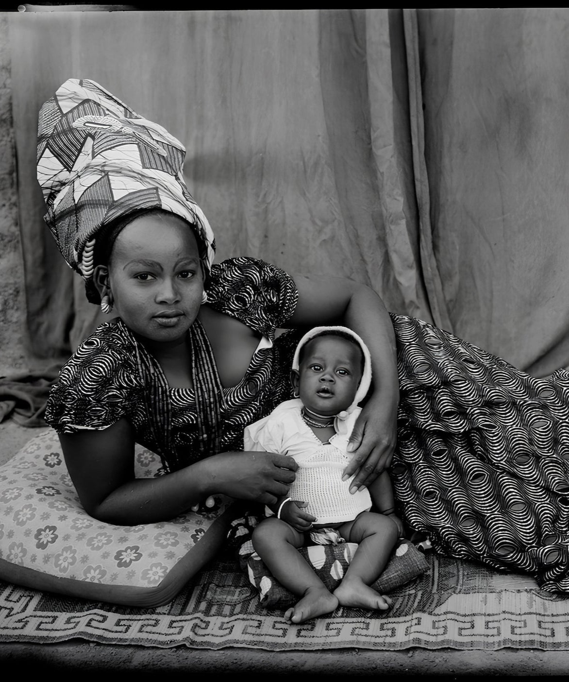 Portrait by Seydou Keïta of a mother in patterned fabric with her baby, a classic example of Malian studio photography